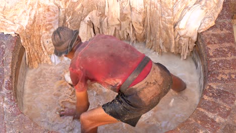 A-man-washing-the-leather-in-a-tannery-in-Fez,-with-his-legs-inside-the-dirty-water