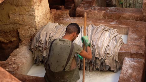 A-man-from-the-back-while-he-is-working-in-a-tannery-in-Fez,-Morocco
