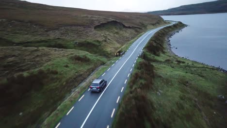 aerial-pan-scenic-view-of-a-car-driving-on-a-road-next-to-the-atlantic-ocean