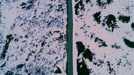 Aerial-top-down-shot-over-highway-road-with-white-snow-covered-on-both-sides-along-mountain-slope