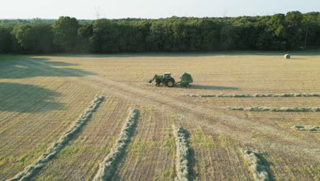 Mostly-a-static-profile-shot-of-driving-tractor-in-large-hay-field-with-hay-lines-and-rows