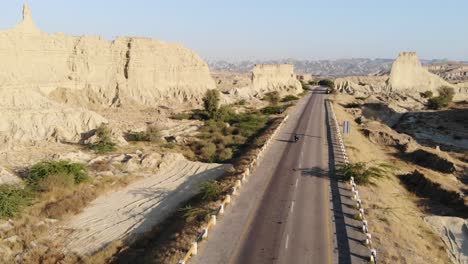 Luftbild-über-Die-Leere-Autobahn-Durch-Den-Hingol-Nationalpark-In-Der-Wüstenlandschaft-Von-Balochistan-Mit-Vorbeifahrendem-Motorrad