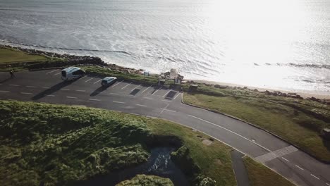 aerial-push-in:-car-park-next-to-the-ocean,-Ireland,-Connemara