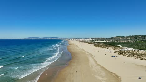 Drone-flying-low-by-the-beach-in-Costa-Da-Caparica,-Portugal