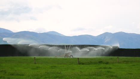 Water-sprinkler-machine-in-vast-agriculture-fields,-distance-view