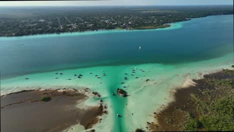 Aerial-view-overlooking-boats-at-the-Pirates-channel-revealing-the-Bacalar-town-in-the-background,-in-Mexico