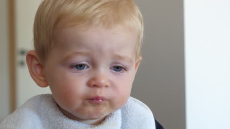 Close-up-of-blond-baby-boy-with-blue-eyes-eating-food