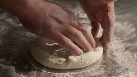 Male-hands-kneads-the-dough-in-closeup-with-flour-on-table