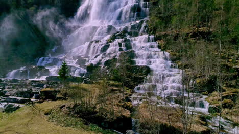 Schöner-Wasserfall-Am-Berghang,-Umgeben-Von-Baumwald-An-Einem-Sonnigen-Tag