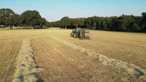 Low-altitude-follow-shot-of-tractor-with-pull-behind-round-hay-baler