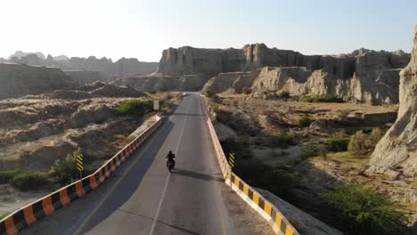 Motorcyclist-Riding-Into-Distance-On-Makran-Coastal-Highway-Road-Beside-Dramatic-Rock-Formations-In-Hingol-National-Park