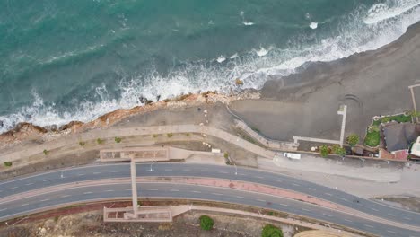 Aerial-top-down-shot-of-cars-on-coastal-road-and-Candado-Beach-in-Malaga-during-sunny-day