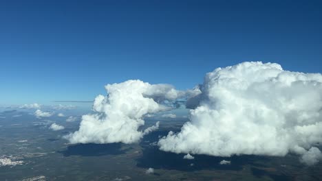 Flying-toward-two-white-cumulus-clouds-during-the-descent-to-Palma-de-Mallorca’s-island,-Balearic-islands,-Spain