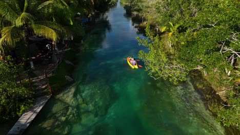 Aerial-view-tracking-people-paddling-in-a-tropical-rainforest-channel,-in-Mexico