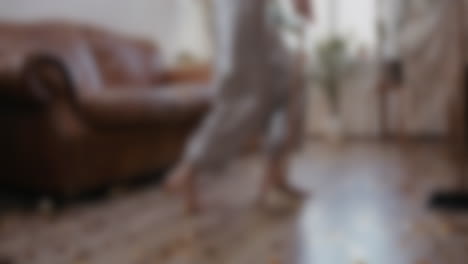 Blurred-shot-of-woman-dancing-while-cleaning-the-house-with-a-broom,-having-fun-while-doing-domestic-household-maintenance