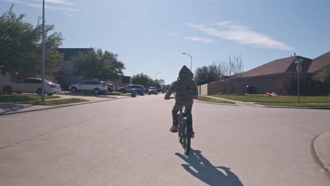 A-boy-rides-his-bike-through-his-neighborhood-at-regular-speed-in-4k