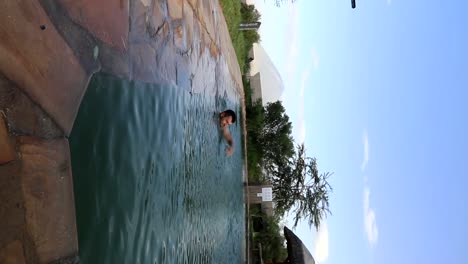 Vertikale-Aufnahme-Eines-Mannes,-Der-In-Einem-Pool-Schwimmt,-Mit-Dem-Vulkan-Ol-Doinyo-Lengai-Dahinter