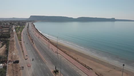 Aerial-Dolly-Right-Over-Marine-Drive-Beside-Beach-Coastline-In-Gwadar-With-Traffic-Going-Past