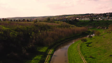 Drone-flying-over-curve-of-countryside-water-canal-in-Moldova