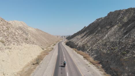 Motorcyclist-Riding-Along-Empty-N10-Makran-Coastal-Highway-Road-Beside-Dramatic-Rock-Formations-In-Hingol-National-Park