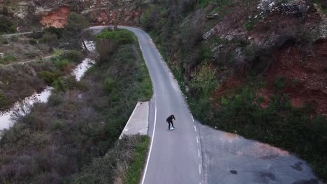Aerial-view-of-young-man-doing-surfskate-on-a-mountain-road