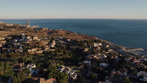 Aerial-flyover-residential-area-located-on-hill-in-Malaga-and-Candado-Beach-with-blue-Ocean-at-sunset