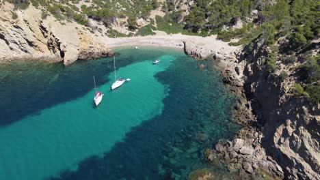 Luftaufnahme-Eines-Strandes-Mit-Türkisfarbenem-Und-Kristallklarem-Wasser-Mit-Verankerten-Booten-Auf-Mallorca,-Balearen