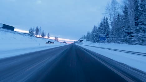 Timelapse-shot-driving-along-a-cleared-highway-with-snow-covered-trees-in-Helsinki