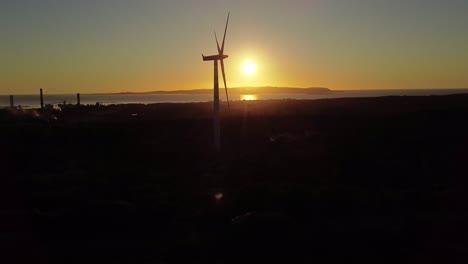 Aerial-shot-of-single-silhouette-Wind-Turbine-spinning-blades-against-sunset-sun