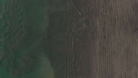 Aerial-flight-above-empty-beach-with-ocean-sand-swirls-in-Costa-Rica