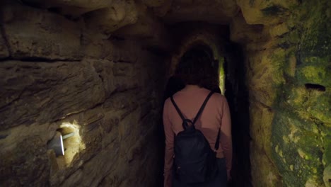 People-Walking-Exploring-Deep-Long-Underground-Stony-Tunnel,-roman-sewers-in-Medina,-Cadiz-Spain