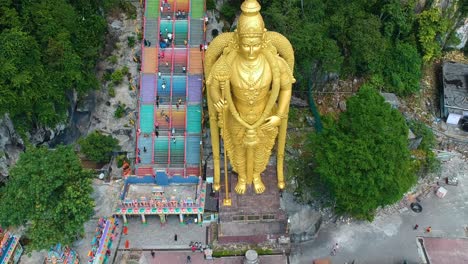 Revealing-aerial-view-of-drone-flying-backwards-recording-batu-caves-with-huge-golden-statue-which-is-a-hindu-shrine-near-Kuala-Lumpur-Malayasia