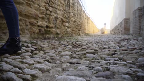 Slow-Motion-Shot-Of-Person's-Feet-Walking-On-Pebble-Ground-In-roman-Rural-Street