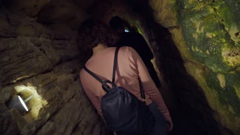 People-Walking-Exploring-Deep-Long-Underground-Stony-Tunnel,-roman-sewers-in-Medina,-Cadiz-Spain