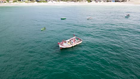 Drone-aerial-scene-of-fishing-boat-drifting-without-people-near-the-beach-calm-sea-with-other-boats-near-Ingles-beach-Florianopolis