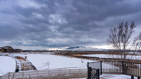 Snowy-field-or-park-with-dark-cloudscape-above-the-mountain-landscape---time-lapse