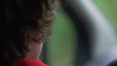 Teenage-boy-drives-car,-close-up-over-the-shoulder,-handheld
