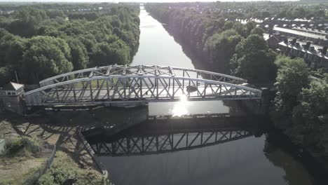 Aerial-view-scenic-old-vintage-steel-archway-traffic-footbridge-lowering-towards-Manchester-ship-canal-crossing