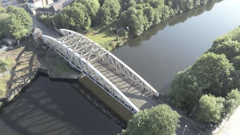 Aerial-birds-eye-view-scenic-old-vintage-steel-archway-car-crossing-footbridge-over-Manchester-ship-canal