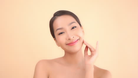 Happy-beautiful-asian-female-touching-her-face-skin-after-cosmetic-spa-treatment,-static-isolated-slow-motion
