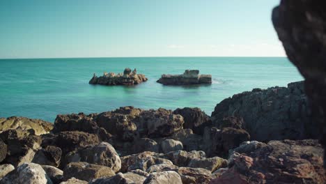 Peaceful-ocean-view-at-shore-with-rock-cliff-with-blue-sky-at-Cascais-Portugal-4K-Jib-Shot
