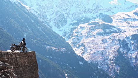 A-man-standing-with-his-bike-and-smoking-at-the-edge-of-the-cliff-at-suicide-point-,-kalpa-,-himachal-pradesh