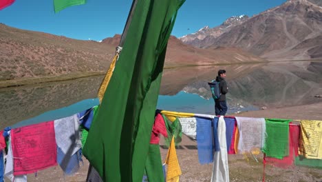 Sideways-moving-shot-of-a-huge-himalayan-lake-with-prayer-flags-at-chadratal-lake-,-spiti-valley
