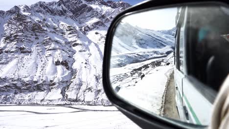 Rear-view-mirror-perspective-of-a-car-driven-in-rough-mountain-terrain-during-winters