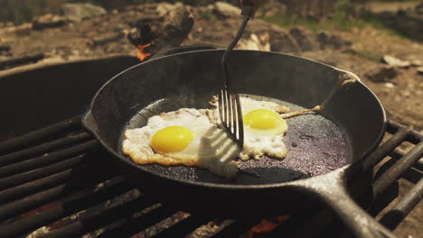 Close-up-cooker-using-spatula-to-adjust-two-fried-eggs-in-the-pan