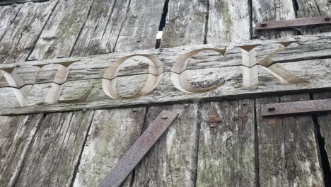 Aged-carved-weathered-unlock-word-in-old-timber-plank-rusty-doorway-dolly-left