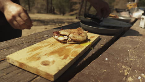 Nahaufnahme-Camper-Verwendet-Das-Messer,-Um-Das-Englische-Muffin-Sandwich-In-Zwei-Hälften-Zu-Schneiden