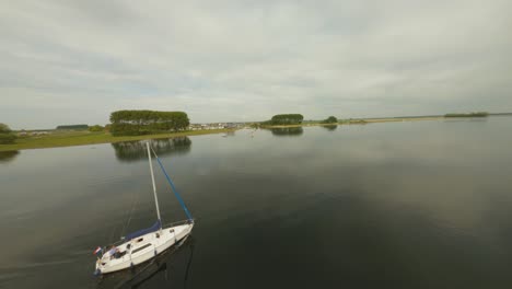 Aerial-drone-flight-above-sailboat-in-calm-Veerse-Meer-lake-water