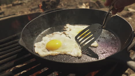 Close-up-cooker-using-spatula-to-separate-two-eggs-cooking-in-the-frying-pan