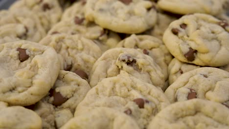 Delicious-cooked-chocolate-chip-cookies-piled-on-pan-ready-to-be-eaten,-close-up-above-pan-left